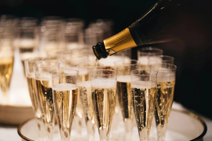 Champagne pouring from a bottle into a group of flutes on a tray